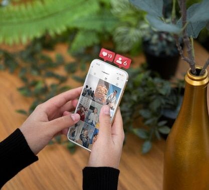 A person scrolling through Instagram on a smartphone with notification icons floating above the screen, representing social media engagement and digital marketing.